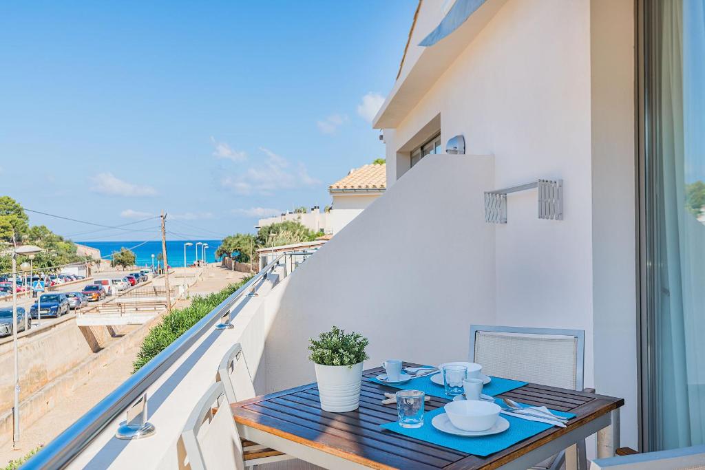 a table on a balcony with a view of the beach at Can Botana Casa 8 - By Dream Villas Pollensa in Cala de Sant Vicenc