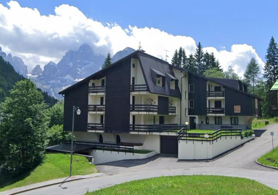 a large apartment building with mountains in the background at Bilocale ad un passo dalle piste in Madonna di Campiglio