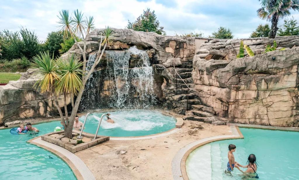 a pool with a waterfall and people swimming in it at Glamping Bretagne in Quimper