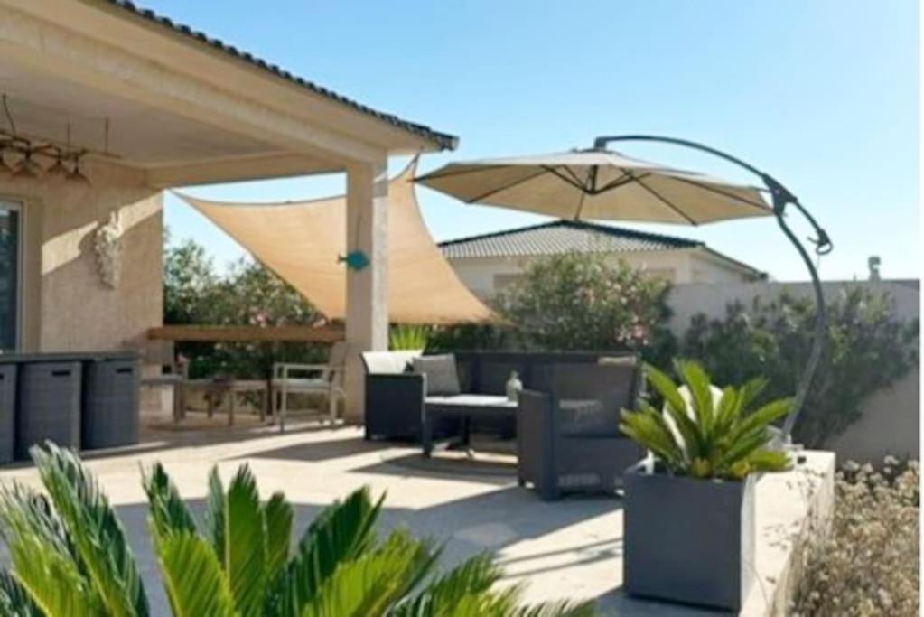 een patio met een parasol en een tafel en stoelen bij "Villa Les Didi" Jacuzzi, proche de la mer in Solaro