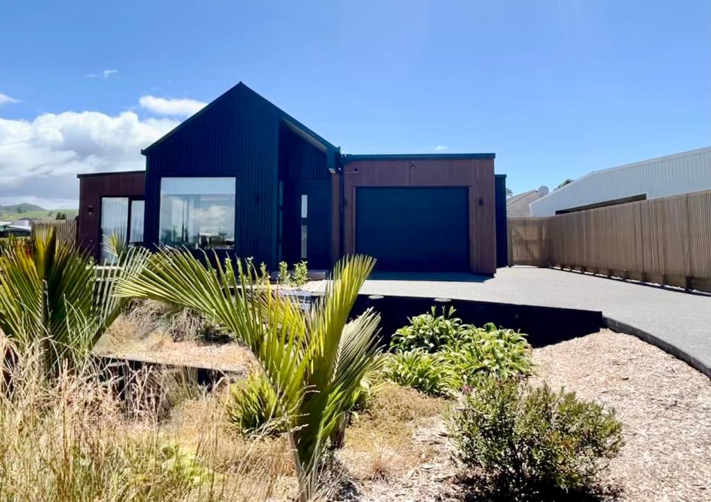 een zwart huis in de woestijn met wat planten bij Sandy Palms - Home Away From Home in Waihi Beach
