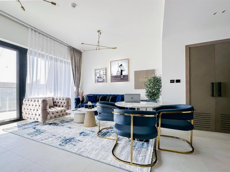 a living room with a table and blue chairs at Trophy - Luxury Casa Cielo Suites in Dubai