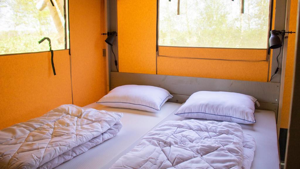 two beds in a room with two windows at Glamping Bretagne in Quimper