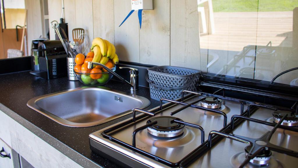 a kitchen stove with a sink and a bowl of fruit at Glamping Bretagne in Quimper