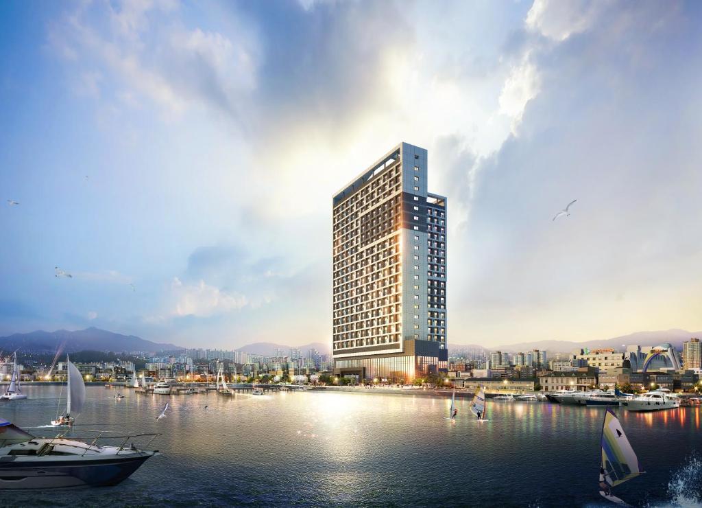 un rendimiento de un edificio alto con barcos en el agua en Sunrise Hotel Sokcho en Sokcho