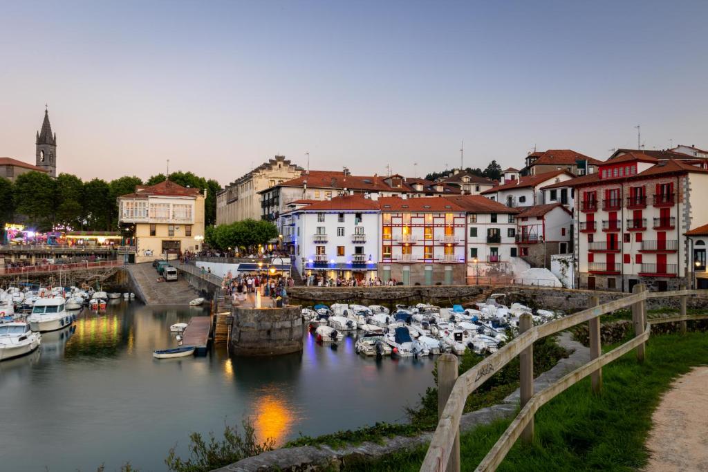 a city with boats in a river with buildings at Hotel&Spa El Puerto in Mundaka