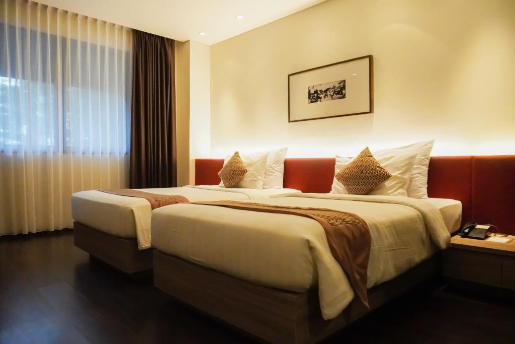 a hotel room with two beds and a window at de JAVA Hotel Bandung in Bandung