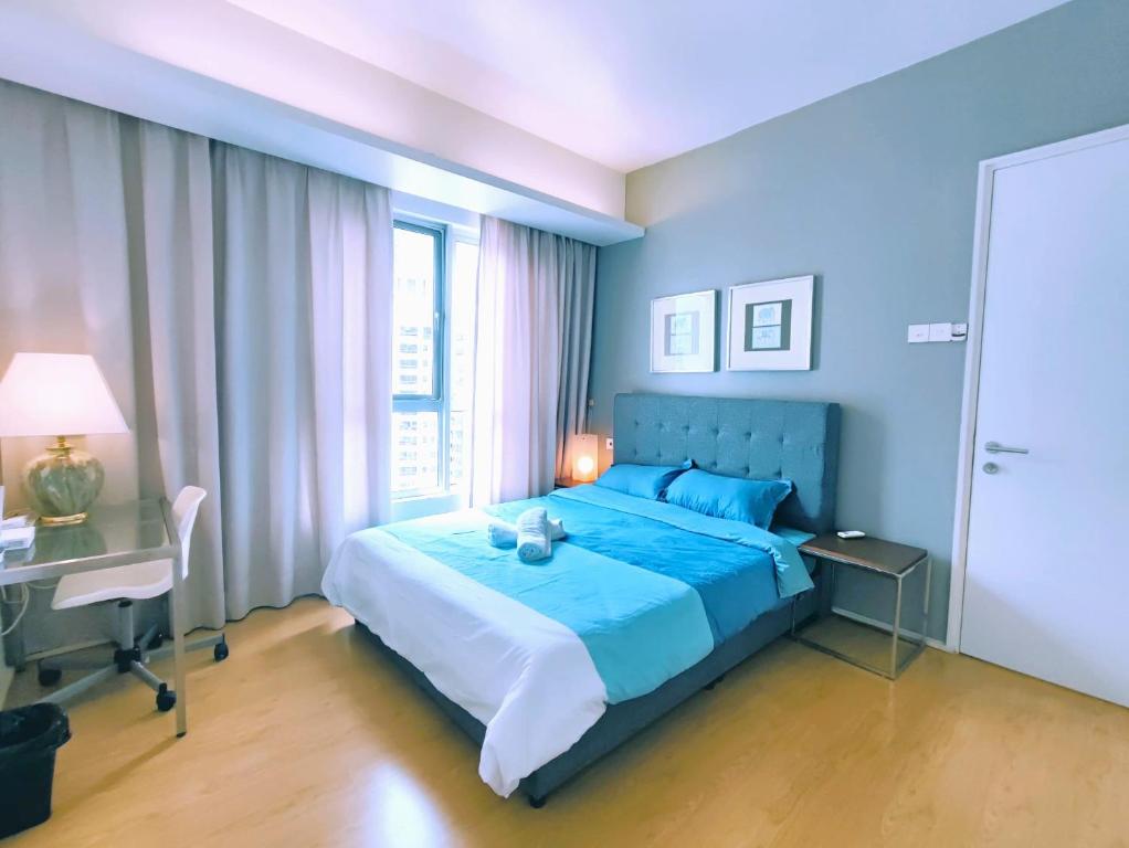 ein blaues Schlafzimmer mit einem blauen Bett und einem Schreibtisch in der Unterkunft 1 Mont Kiara - Sri Hartamas -International Schools - Kiara 1 in Kuala Lumpur