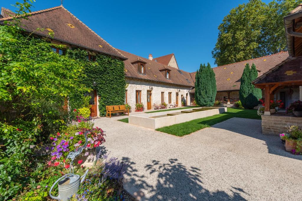 a courtyard of a house with flowers and plants at Hotel Le Clos De La Vouge in Vougeot