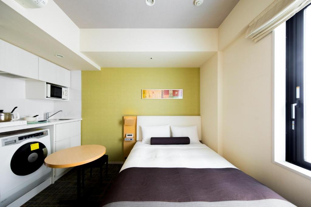 a small bedroom with a bed and a table at Tokyu Stay Kamata - Tokyo Haneda in Tokyo