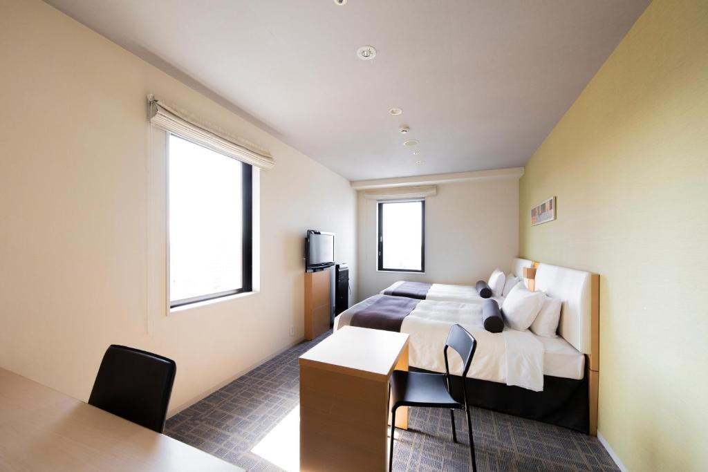 a bedroom with a bed and a desk and two windows at Tokyu Stay Kamata - Tokyo Haneda in Tokyo