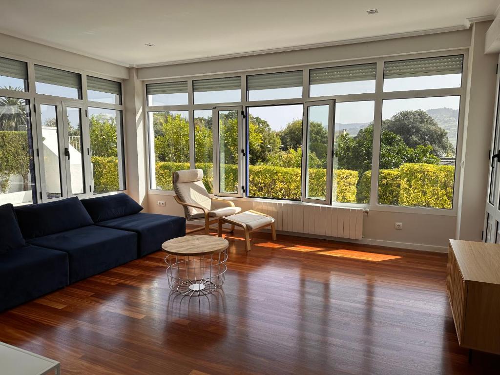 sala de estar con sofá azul, sillas y ventanas en CASA AZUL SANTA KATALINA en Mundaka