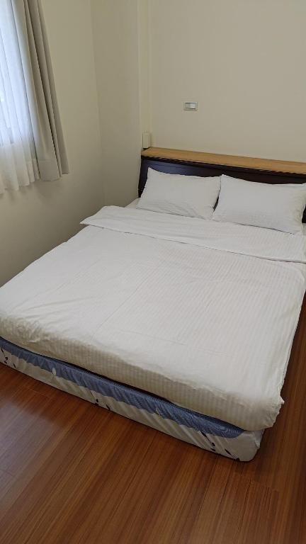 a bed with white sheets and pillows on a wooden floor at Taroko Sialin Coffee Farm Homestay in Xiulin