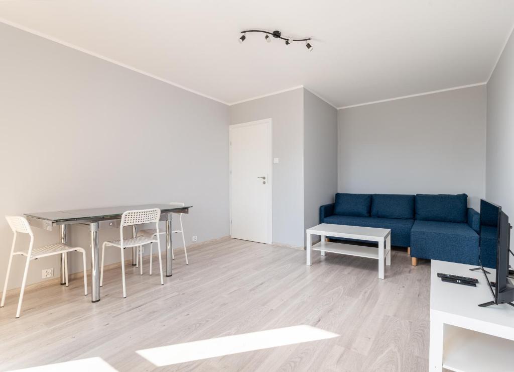 ein Wohnzimmer mit einem blauen Sofa und einem Tisch in der Unterkunft Osiedle Kombatantów Standard Apartment in Krakau