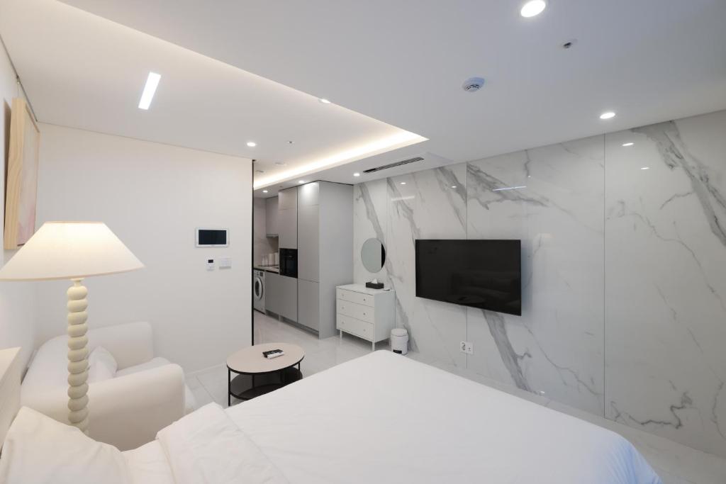 a white bedroom with a bed and a tv on a wall at Zizel Raonjae 2 in Seoul