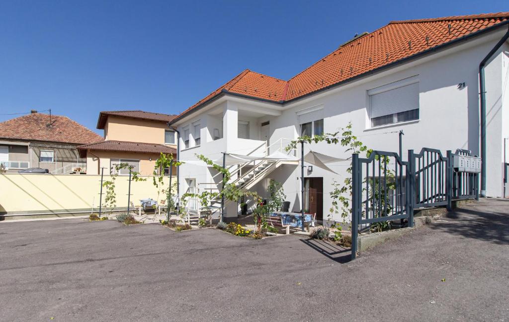 een wit gebouw met een poort op een parkeerplaats bij Déli Terasz B Apartman Free parking, self-check-in anytime in Győr