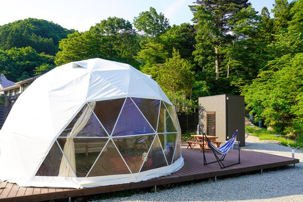 a tent with a table and a chair on a deck at glampark Akasawa Onsen Tochigi in Nasushiobara