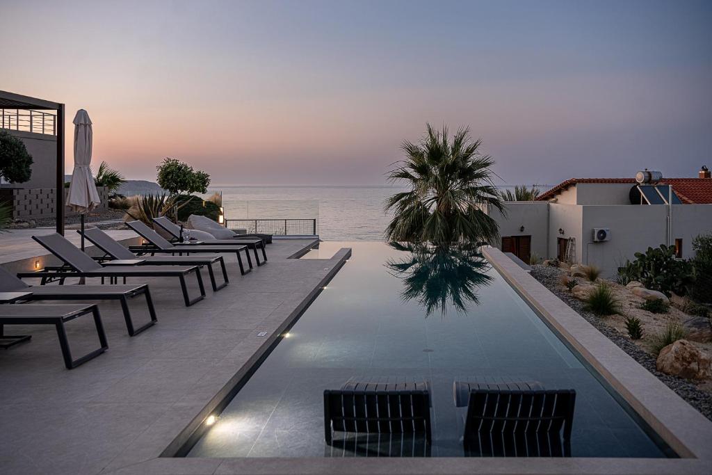 een zwembad met stoelen en de oceaan op de achtergrond bij AGAVE HILL LUXURY HOUSE in Chania