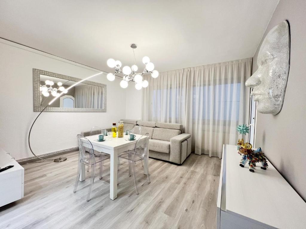 een witte woonkamer met een tafel en een bank bij Cosy Montroig Sitges in Sitges