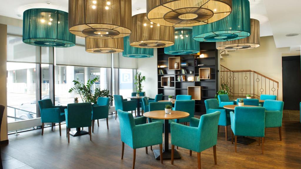 a restaurant with blue chairs and tables and chandeliers at Hestia Hotel Seaport Tallinn in Tallinn