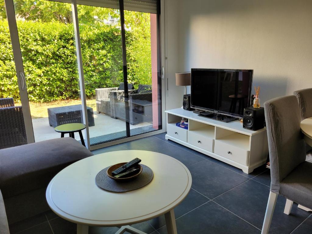 a living room with a television and a table with a hat on it at Appartement avec grand jardin reposant in Le Mans