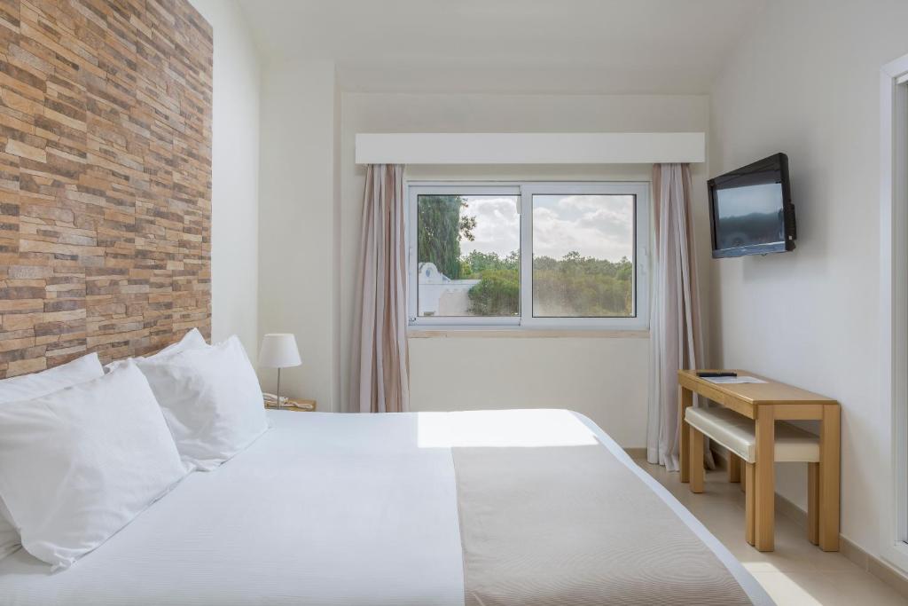 a bedroom with a white bed and a window at Vilar do Golf in Quinta do Lago