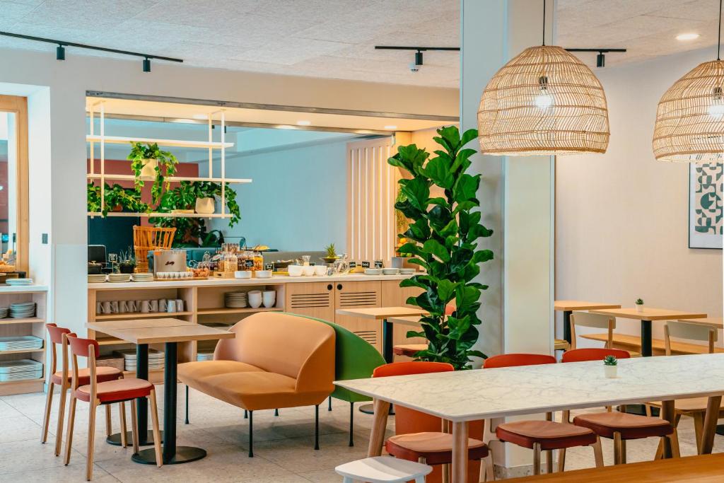 um restaurante com mesas e cadeiras e uma cozinha em Kyriad Marseille Palais Des Congrès – Vélodrome em Marselha