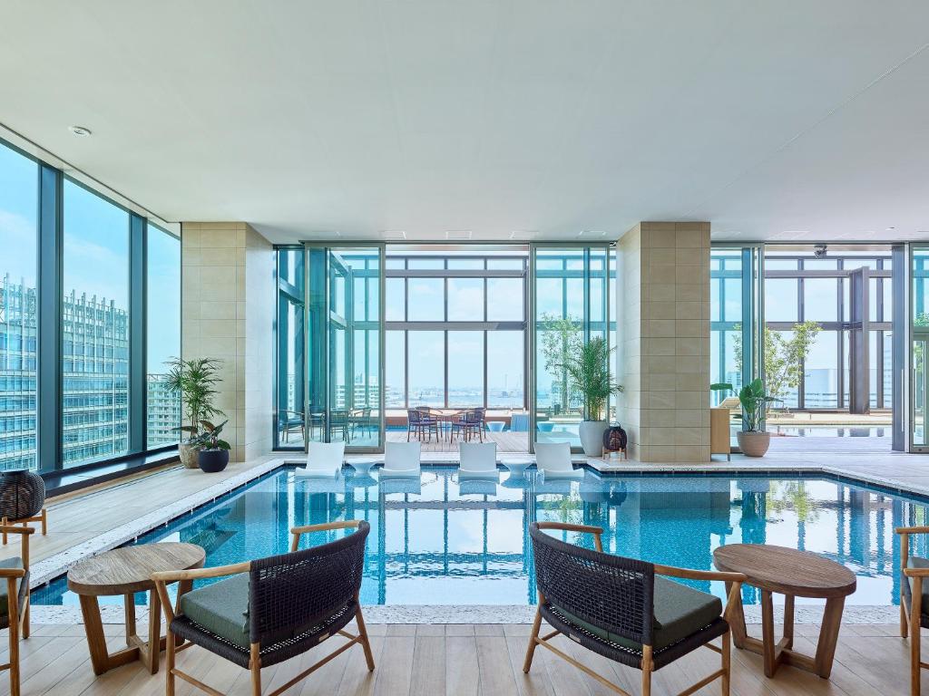 a hotel pool with chairs and tables and windows at Mitsui Garden Hotel Yokohama Minatomirai Premier in Yokohama