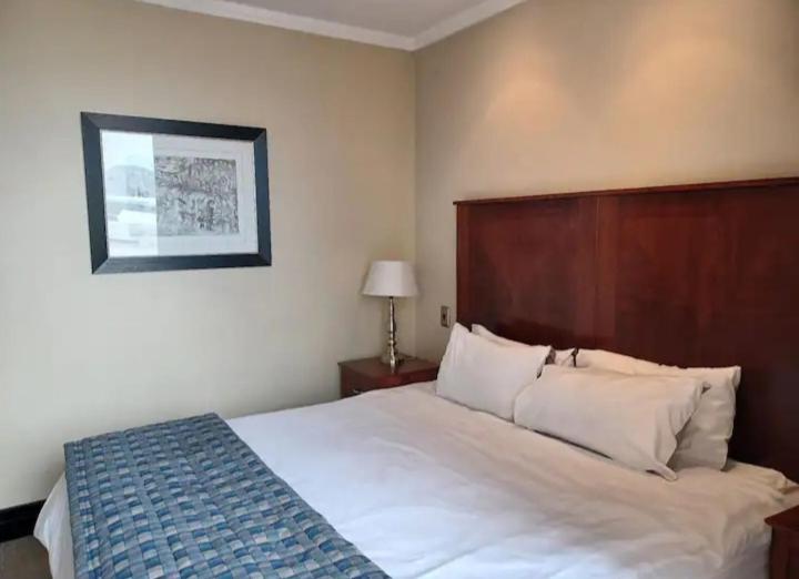 a bedroom with a large bed with a wooden headboard at Luxurious apartments in Johannesburg
