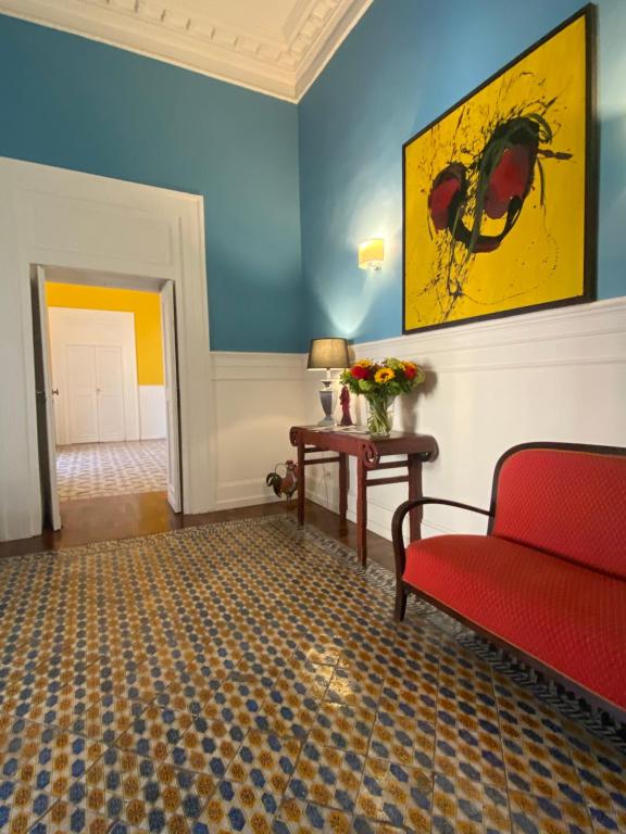 B&B Palazzo Mirelli في نابولي: غرفة معيشة مع كرسي احمر وجدران زرقاء