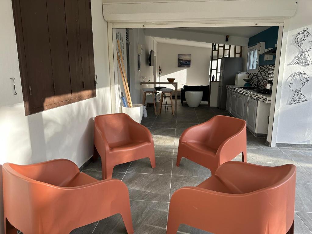 a living room with orange chairs and a kitchen at Villa Tiago in La Trinité