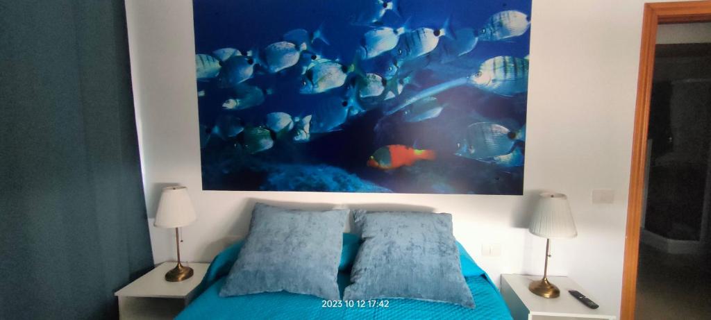 - une chambre dotée d'un lit bleu et d'une peinture murale dans l'établissement Nurea, à La Restinga