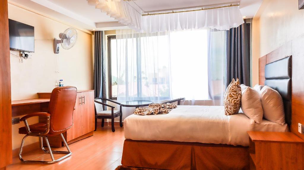 a hotel room with a bed and a desk and a window at Grand Duke Hotel ,Homa Bay in Homa Bay