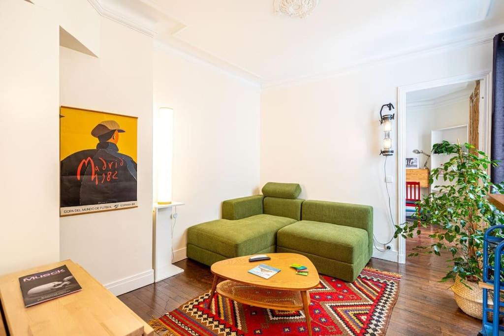 een woonkamer met een groene bank en een tafel bij GuestReady - Wonderful stay near Père-Lachaise in Parijs