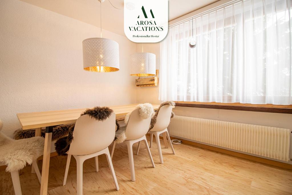 jadalnia z drewnianym stołem i białymi krzesłami w obiekcie Marlenca w mieście Arosa