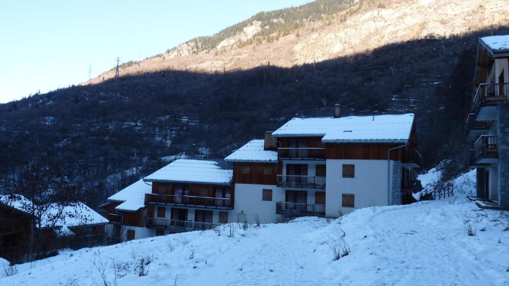 un edificio nella neve con una montagna sullo sfondo di Orelle 3 Vallées - 2 pièces 5/6 personnes a Orelle