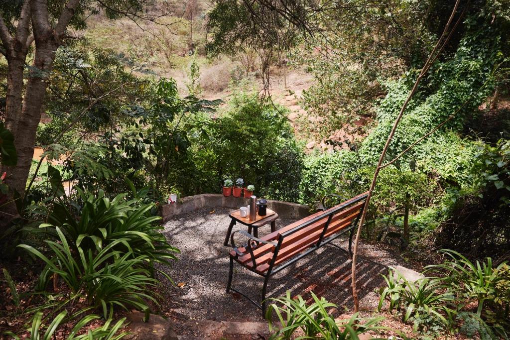 a bench in a garden with a table on a swing at Villa Rock Stop Falls Gigiri in Nairobi