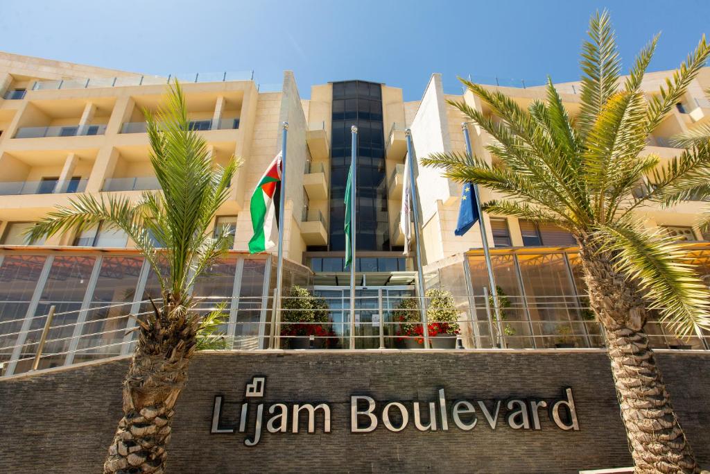 a hotel with palm trees in front of a building at Lijam Hotel in Amman