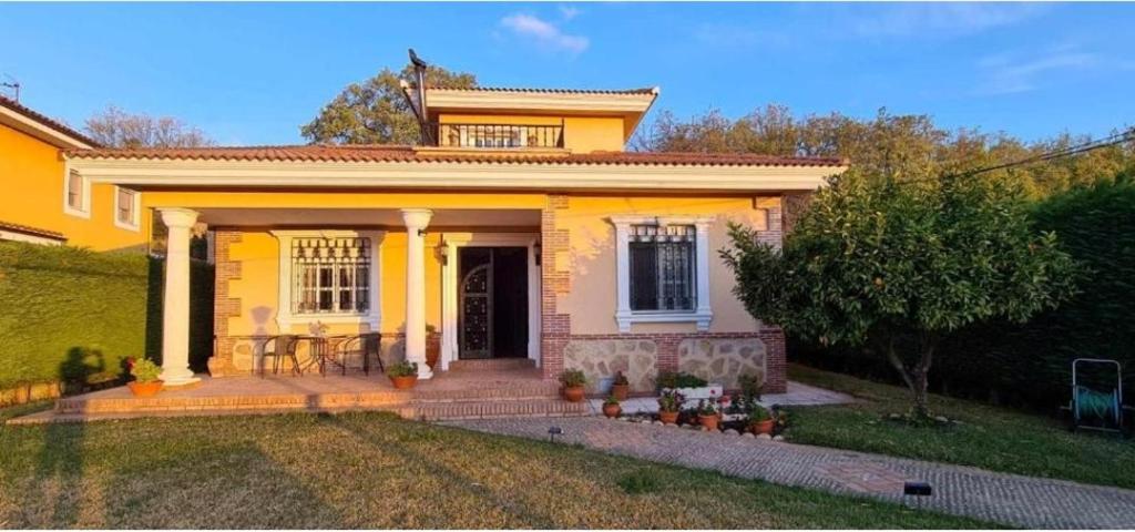 Casa amarilla con porche delantero con mesa en Casa Rural El Camino de Yuste en Cuacos de Yuste