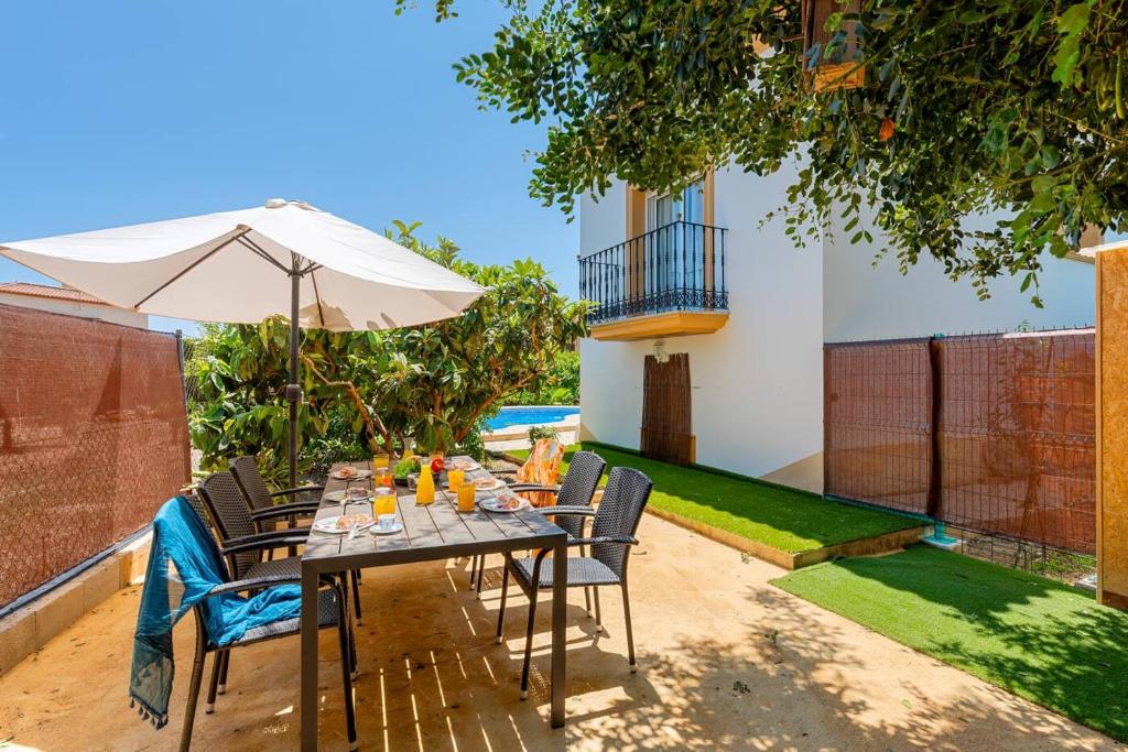 een tafel met stoelen en een parasol in de tuin bij Villa Serena - PlusHolidays in Calpe