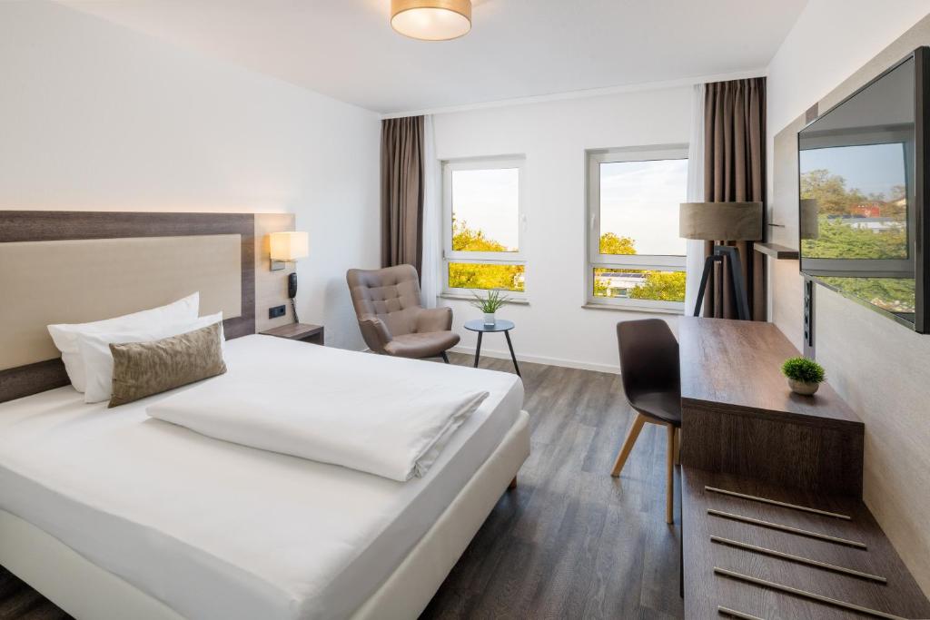 ルートヴィヒスハーフェン・アム・ラインにあるHotel Newton Ludwigshafenのベッドとデスクが備わるホテルルームです。