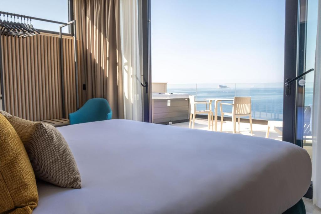 een slaapkamer met een bed en uitzicht op de oceaan bij Deep Blu Boutique Hotel in Żurrieq