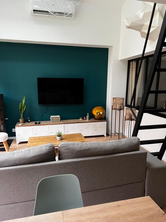 ein Wohnzimmer mit einem Sofa und einem Flachbild-TV in der Unterkunft L’Usine in Concarneau