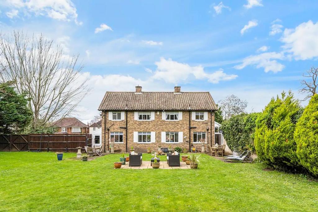 a large brick house with a green yard at Hidden Cottage with Parking in Esher Surrey - Pass the Keys in Esher