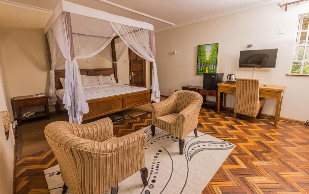 a bedroom with a bed and two chairs and a desk at The Blixen Resort & Spa in Nairobi