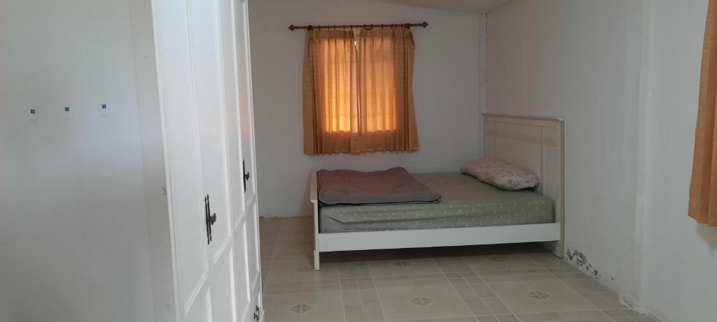 um pequeno quarto com uma cama e uma janela em โฮมสเตย์แม่ปราณี1 