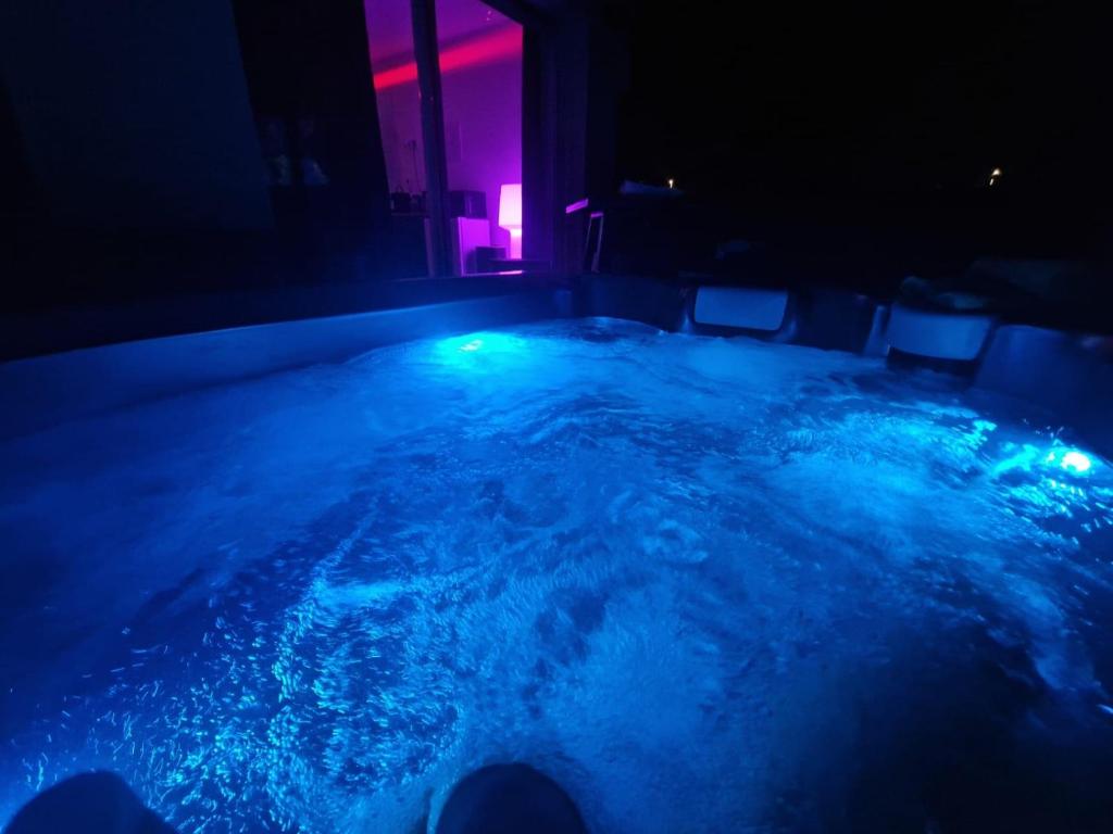 uma banheira de hidromassagem num quarto com luzes azuis e rosa em Studio chic jacuzzi em Portet-sur-Garonne