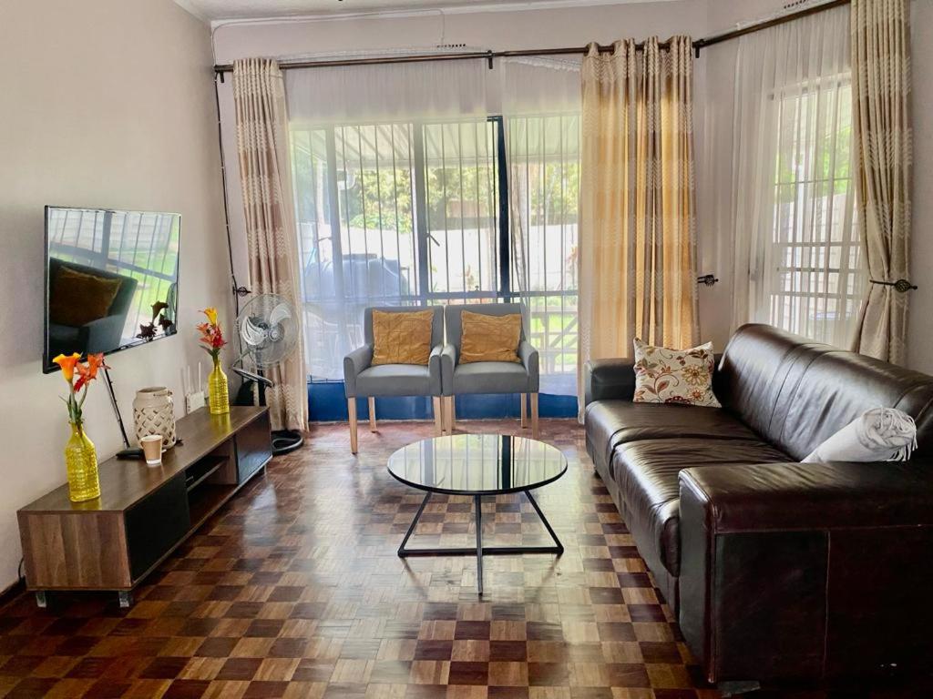 uma sala de estar com um sofá e uma mesa em Lovely 2 bed apartment with garden - 2047 em Harare