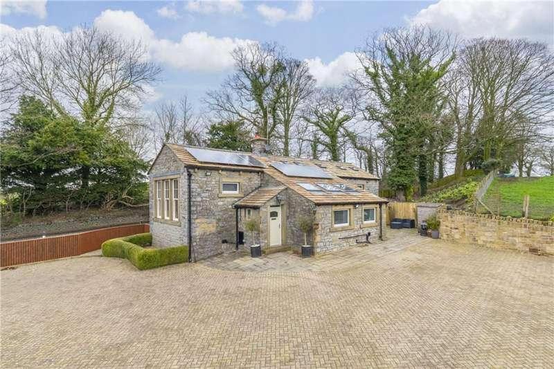 a large stone house with a large driveway at old school house in Skipton