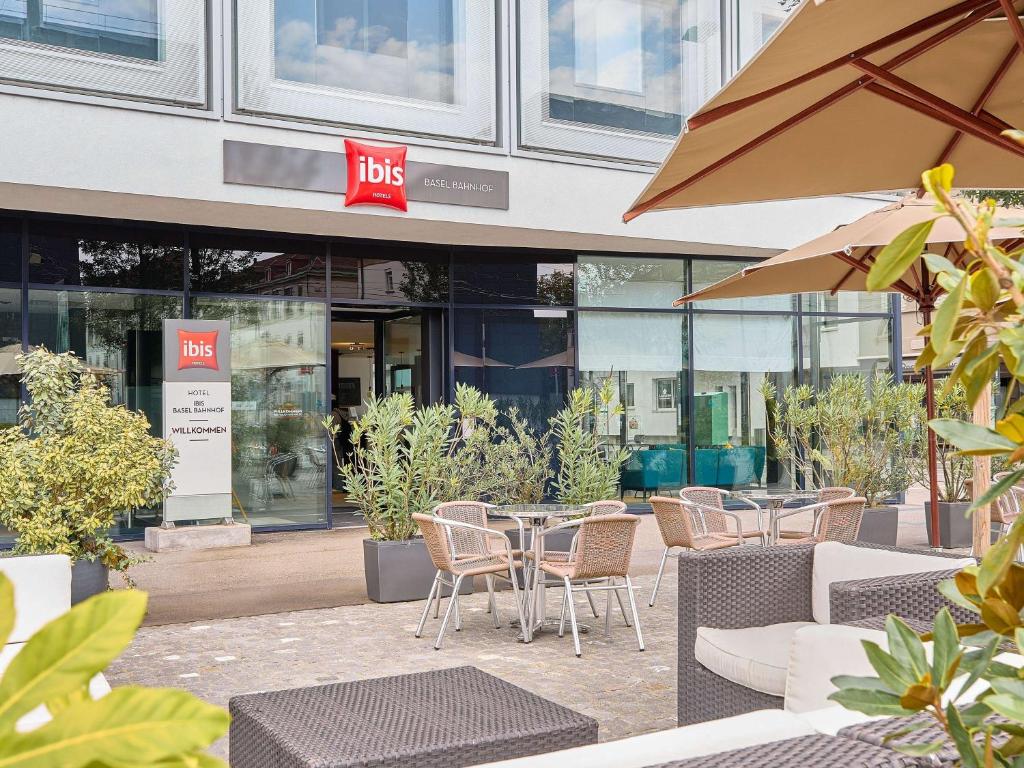 um café com mesas e cadeiras em frente a um edifício em ibis Basel Bahnhof em Basileia
